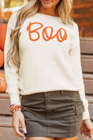 Ivory crewneck sweater with orange "Boo" appliqué, casual fall style.