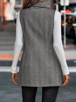 Dark gray herringbone tailored vest with a collared neckline, worn over a white long-sleeve top.
