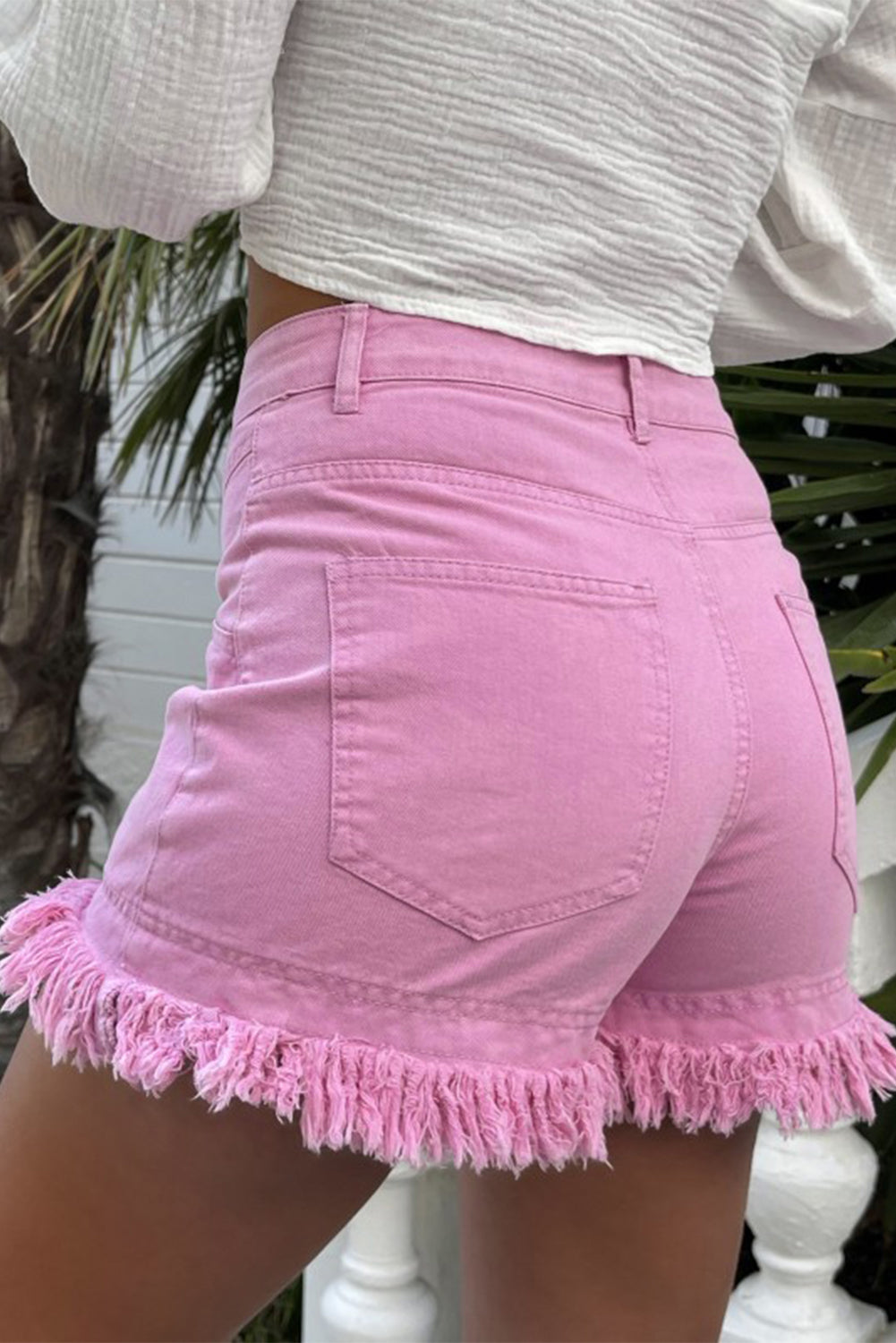Pink denim shorts with high rise and frayed hem detail.