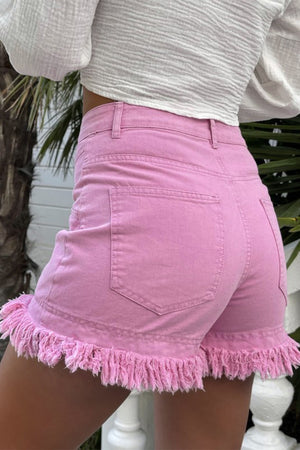 Pink denim shorts with high rise and frayed hem detail.