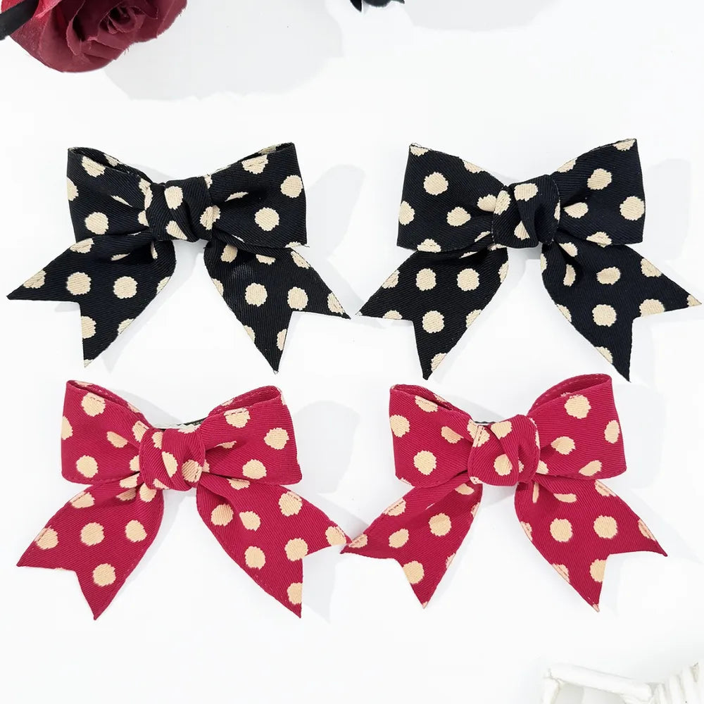 Polka dot bow barrettes in black and deep red, a 2-piece set.