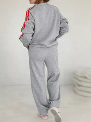 Grey loungewear set with red stripes on sleeves and pants. Crewneck sweatshirt and wide-leg pants.