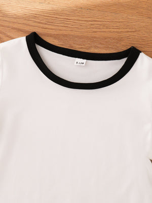 White baby outfit with black trim neckline and size tag