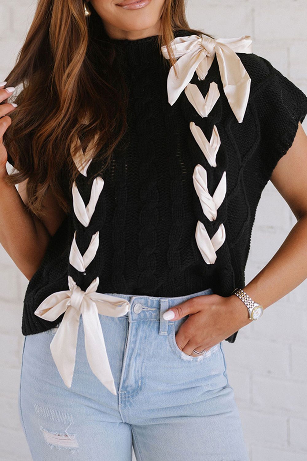 Black cable knit sleeveless sweater with satin lace-up detail and bows