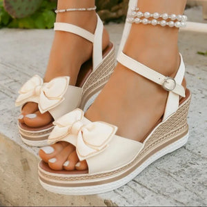 Ivory espadrille wedge sandals with bow detail and ankle strap.