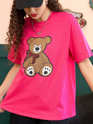 Pink graphic t-shirt with a teddy bear applique and mesh sleeves.