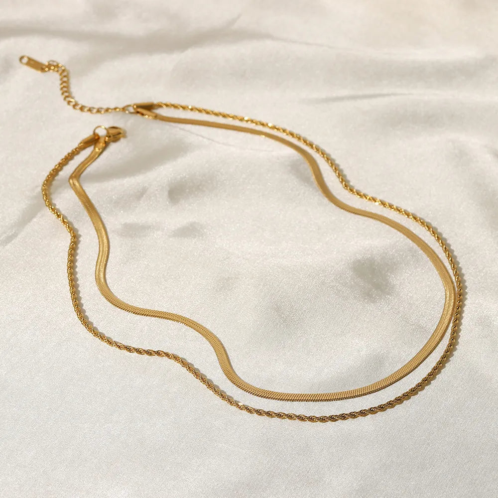 Gold serpentine and rope chain necklace duo on white satin.