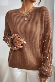 Brown cable knit sweater with pearl embellishments on the sleeves.