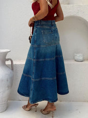 Plus high-waisted denim A-line skirt in dusty blue with tiered panels and back pockets.