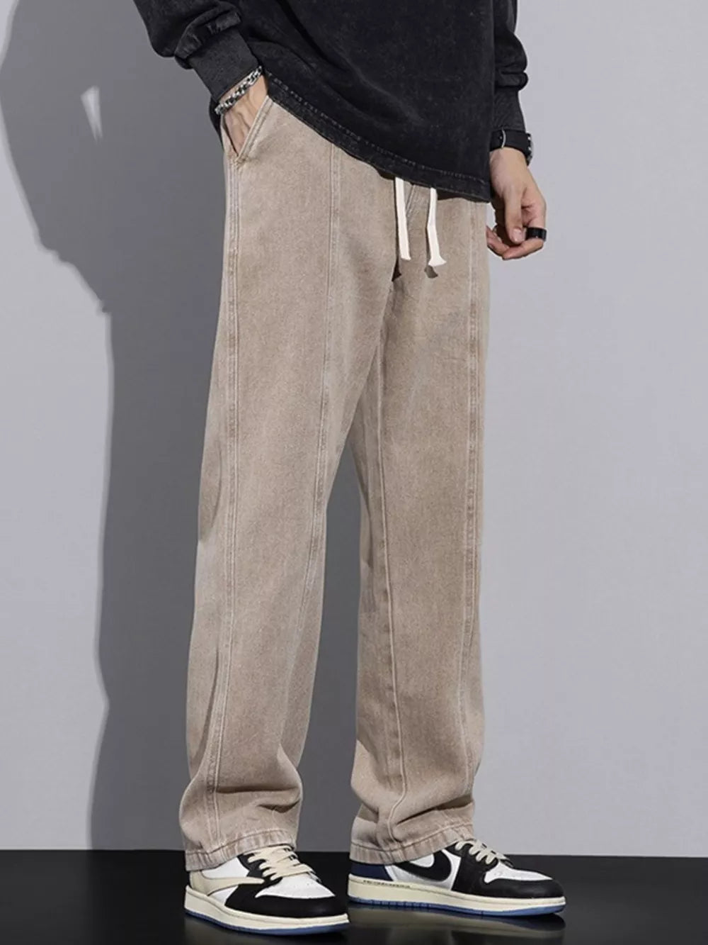 Tan cotton relaxed fit jeans with drawstring waist and front seam detail.