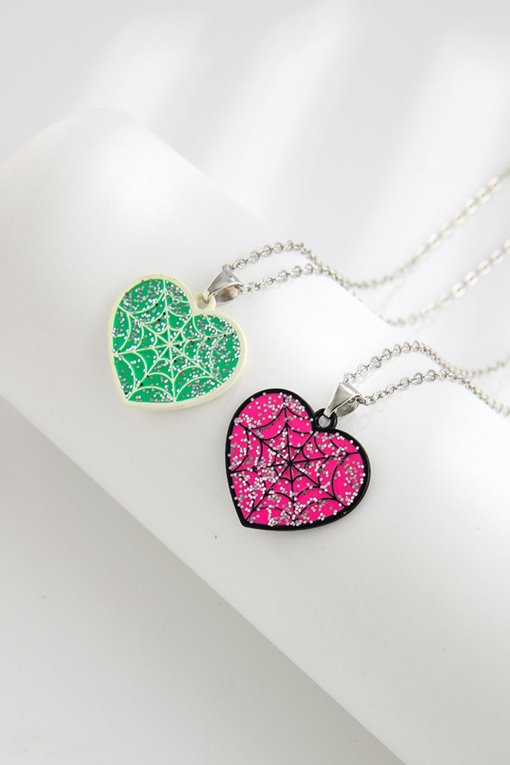 Spooky season heart necklaces in green and pink with glitter spiderwebs.