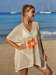 Cream crochet beach cover-up with orange daisy appliqué and V-neck.