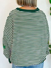 Dark green and cream striped boatneck pullover with clover appliqué on sleeve.