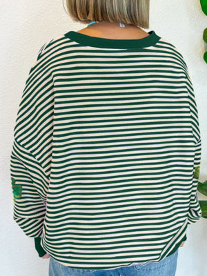 Dark green and cream striped boatneck pullover with clover appliqué on sleeve.