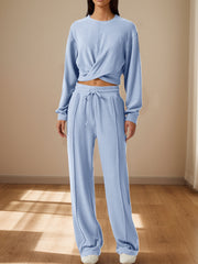 Light blue knit loungewear set with a cross-front cropped top and wide-leg drawstring pants.