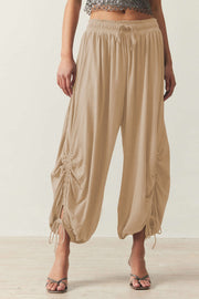 Tan gathered ankle-tie balloon trousers with drawstring waist and ruched side detail.