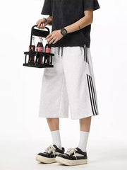 Grey sweatpants with drawstring and black side stripes, cropped length.