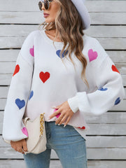 White knit sweater with bubble sleeves and a scattered heart motif in pink, red, and blue.