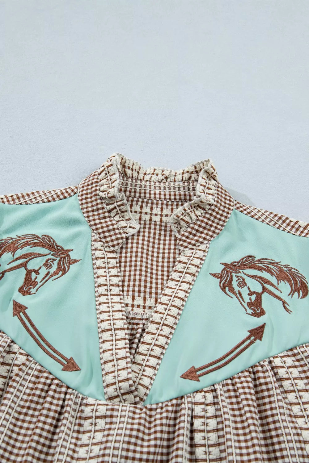 Embroidered yoke gingham puff sleeve shirt with horse detail and ruffled collar.
