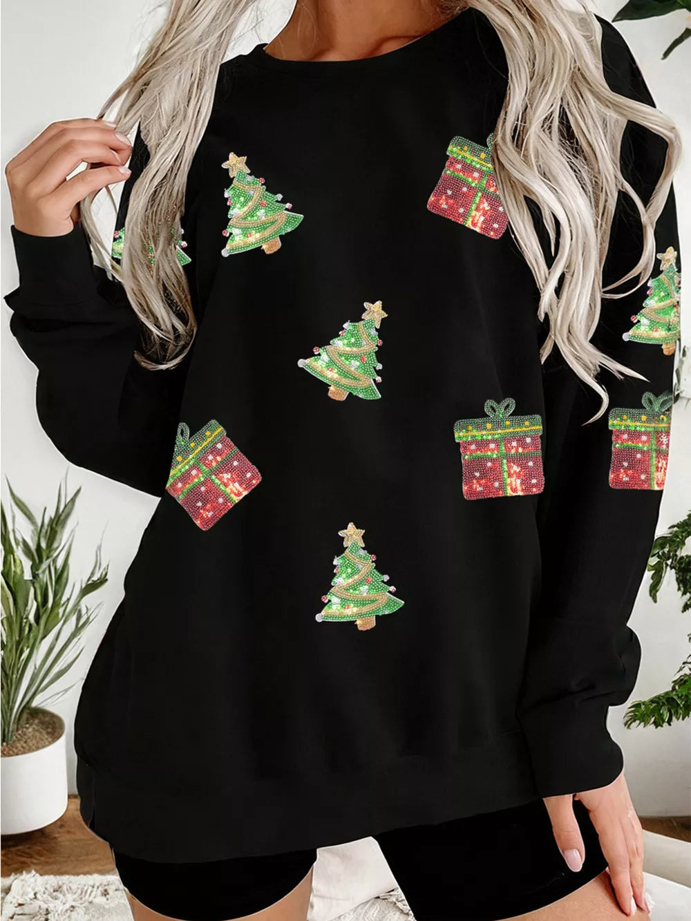 Black crew neck sweatshirt with sequin Christmas trees and gift boxes.