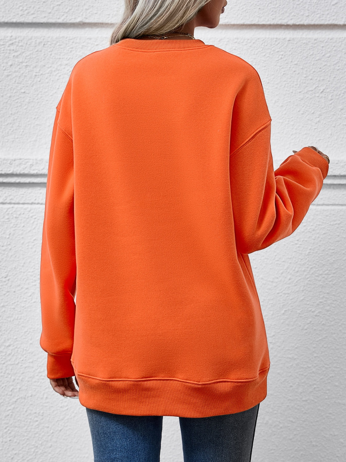 Orange crewneck sweatshirt with ribbed cuffs and hem, relaxed fit.