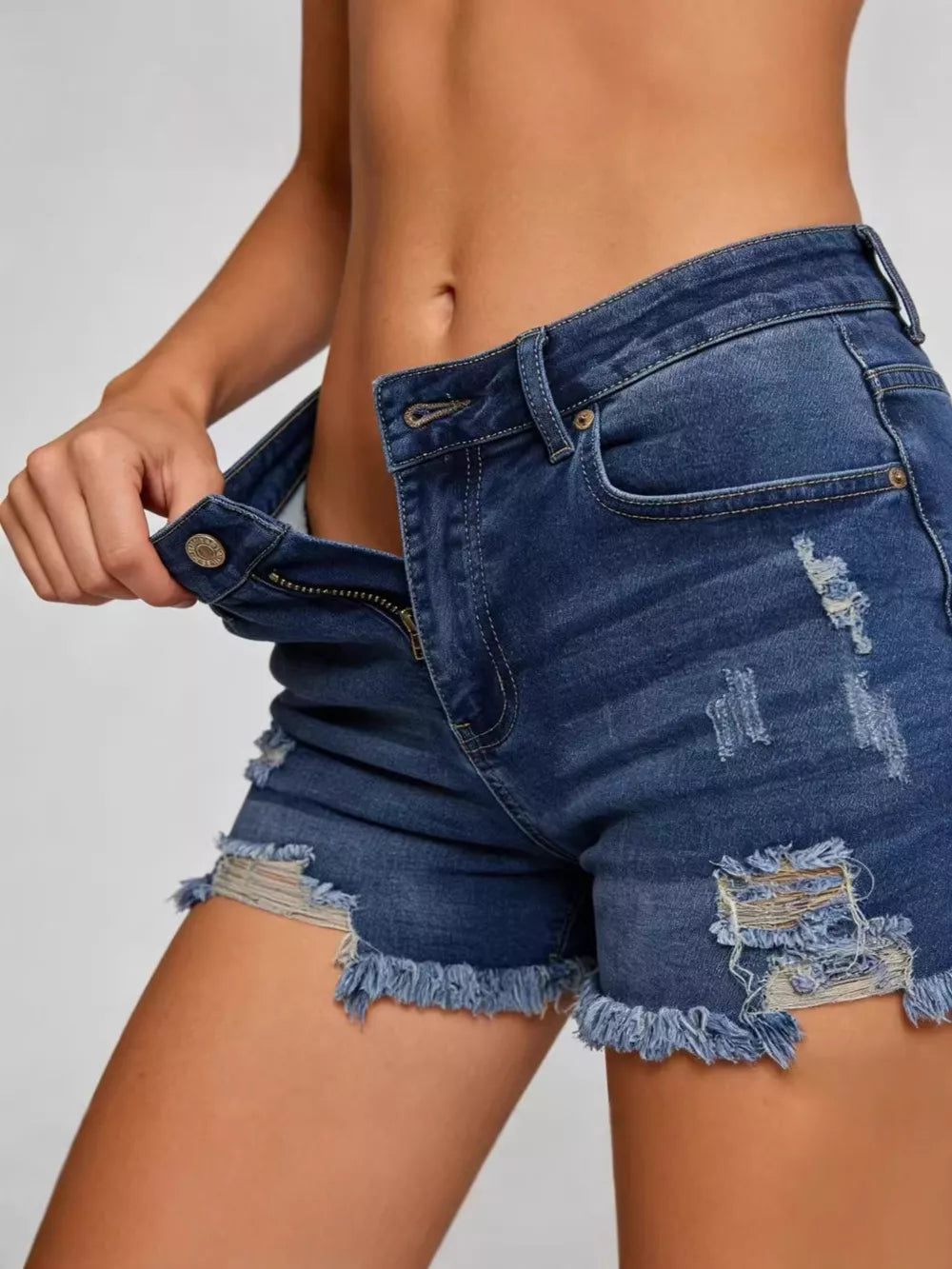 Distressed dark blue denim shorts with raw frayed hem and button fly.