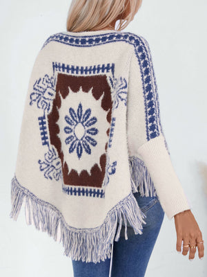Cream knit poncho with Aztec motif, blue trim, and fringe detail.