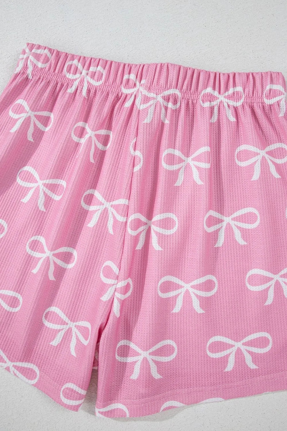 Pink ribbed lounge shorts with allover white bow print and elastic waistband.