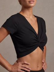 Black ribbed cropped t-shirt with short sleeves and a V-neck twist front detail.