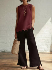 Wine red sleeveless tank top with scalloped hem, styled with black wide-leg pants and a straw bag.