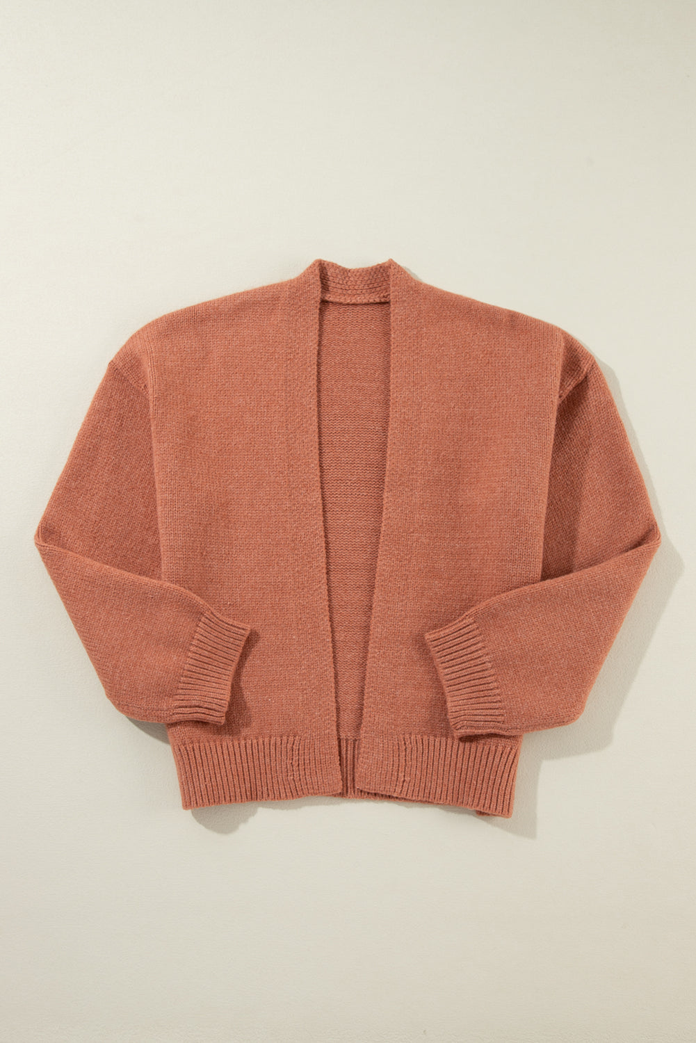 Open-front cropped knit cardigan in burnt coral with ribbed cuffs and hem.