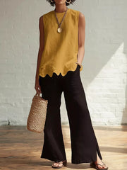 Yellow sleeveless tank top with scalloped hem, styled with black wide-leg pants.