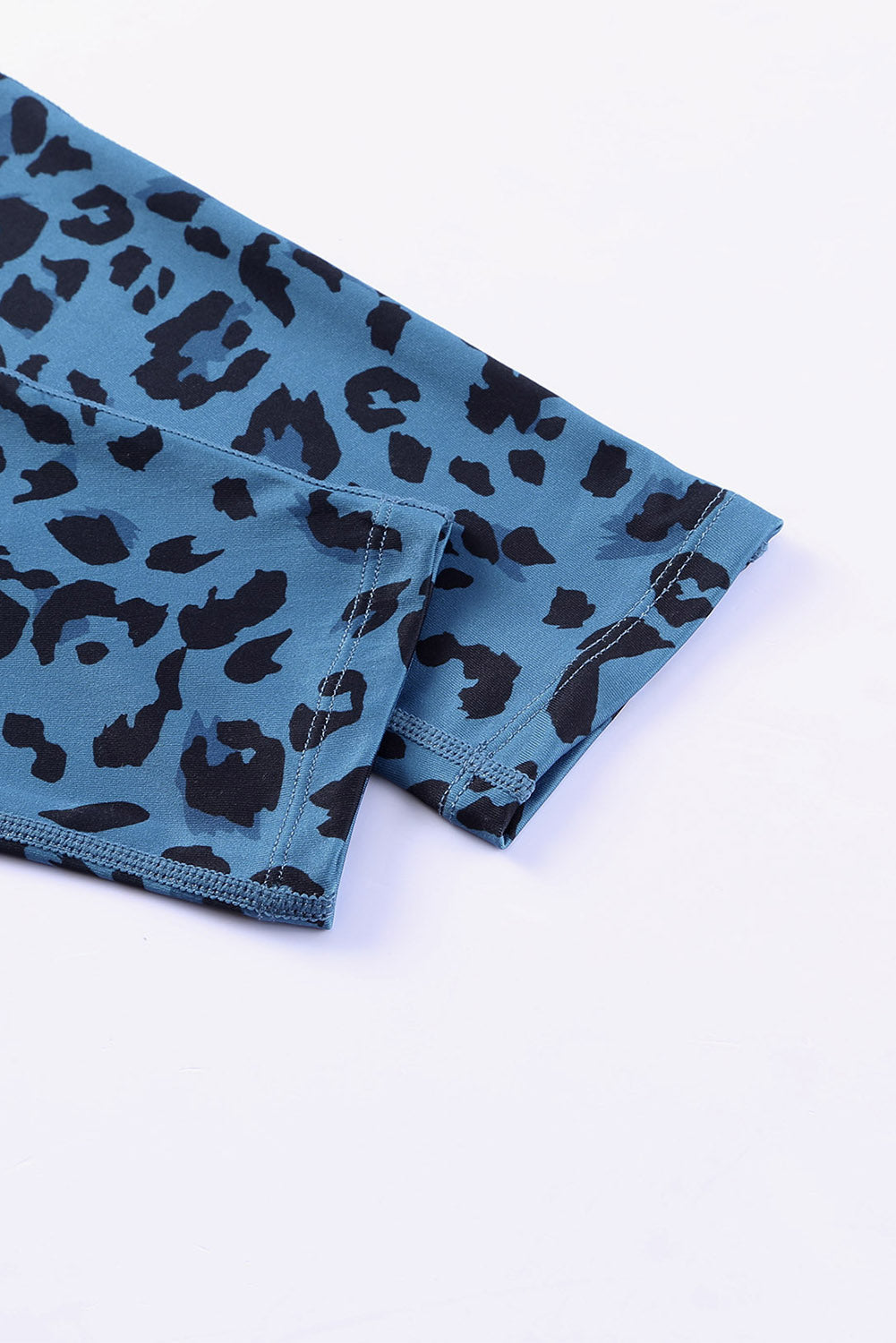 Sky blue leopard print performance leggings with black spots and visible stitching detail.