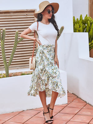 Asymmetric wrap skirt with leaf print in white, green, and yellow, featuring ruffled hem.
