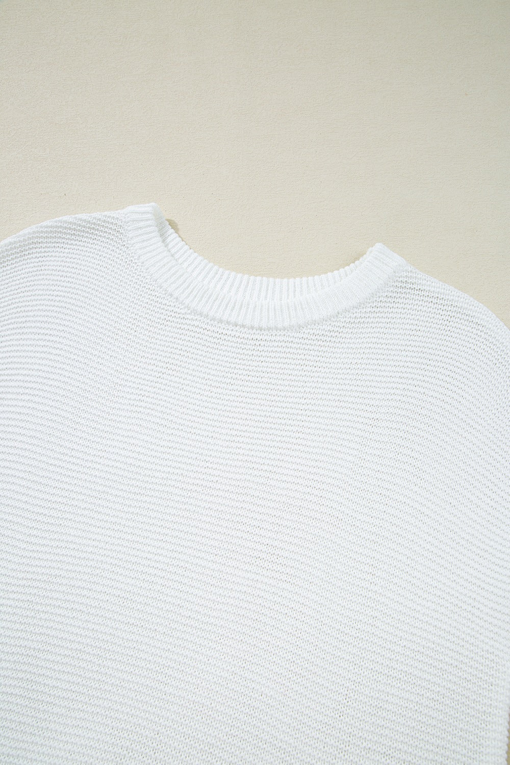 White boxy knit crop top with crew neck and ribbed trim.