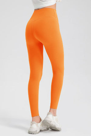 Orange high-waist performance leggings with sculpting seams and a V-cut back detail.
