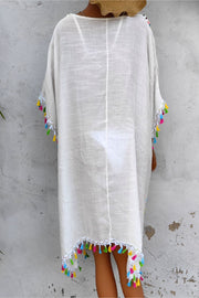 White kaftan dress with colorful tassel trim on sleeves and hem