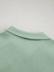 Sage zip-up jacket detail with ribbed collar and cotton fabric.
