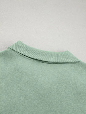 Sage zip-up jacket detail with ribbed collar and cotton fabric.