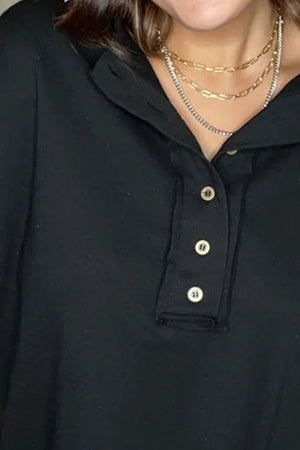 Black henley sweatshirt with button placket and layered necklaces.