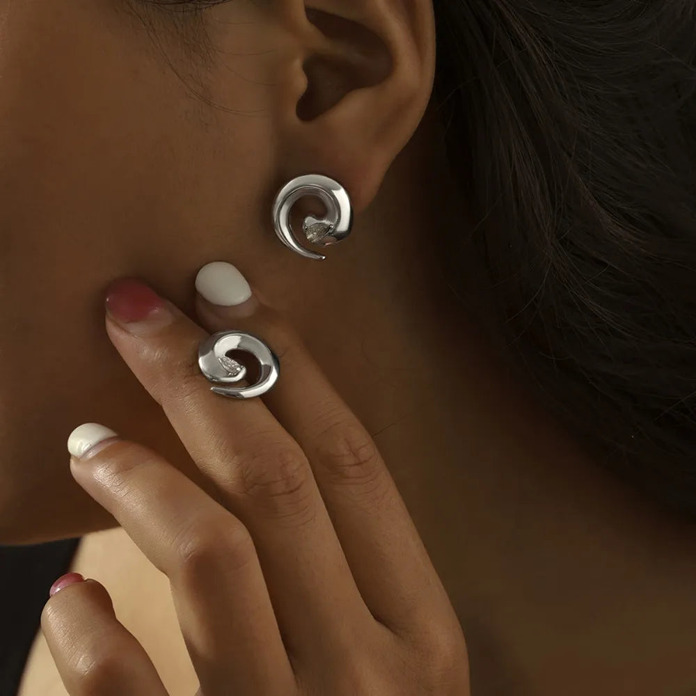 Silver sculptural zirconia swirl stud earrings and matching ring.