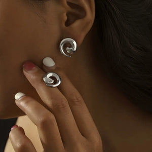 Silver sculptural zirconia swirl stud earrings and matching ring.