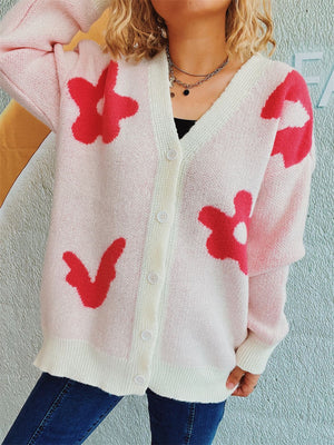 Blush pink acrylic cardigan with red floral appliqué, V-neck, button front, and ribbed trim.