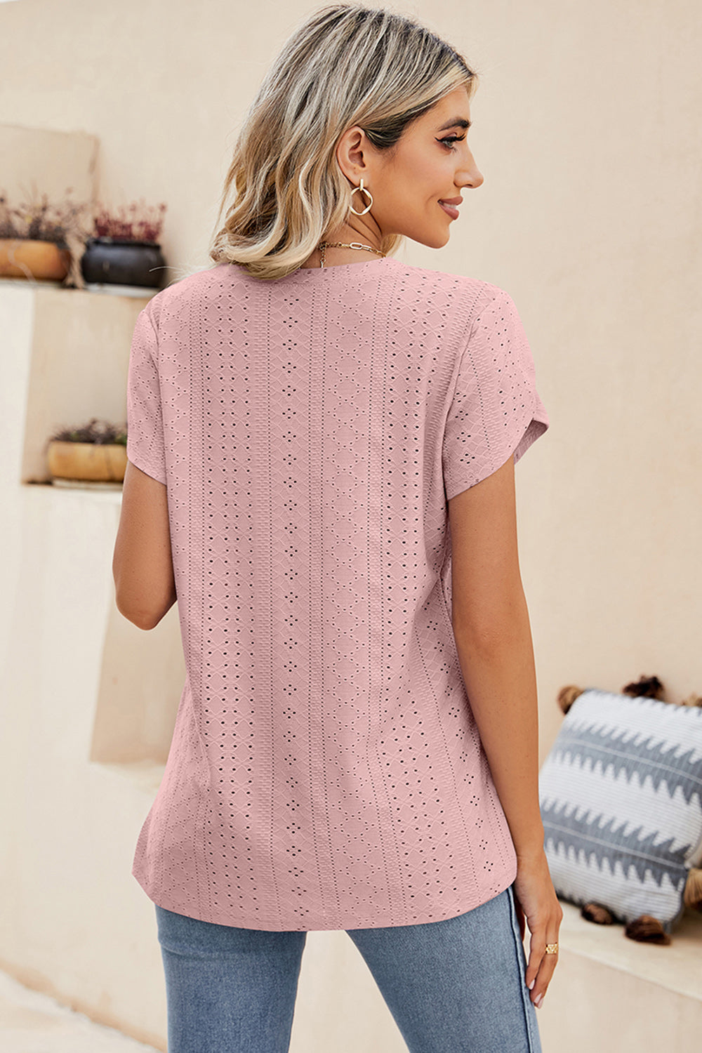 Blush pink eyelet v-neck top with short sleeves and a casual fit.
