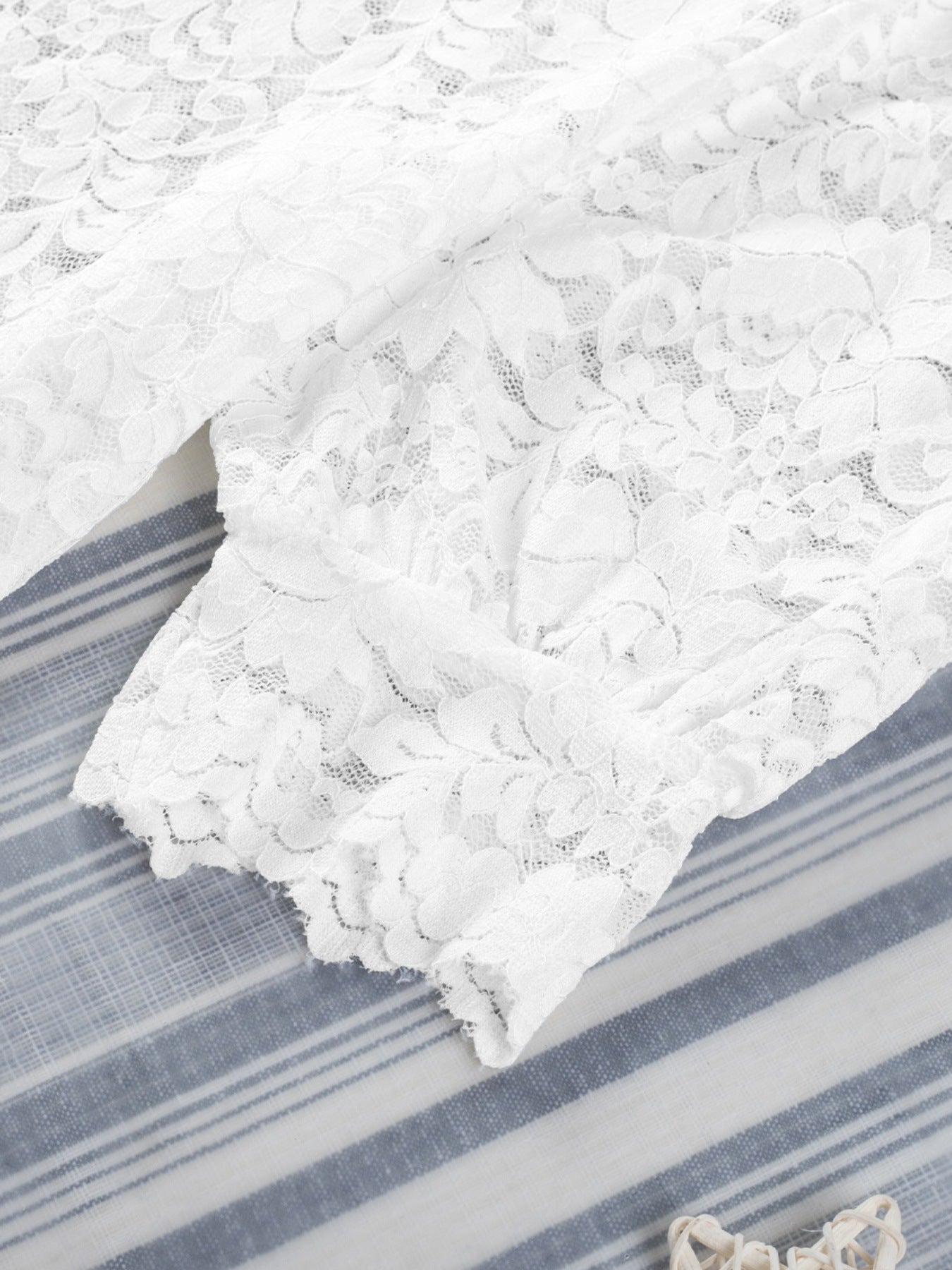 White lace short sleeve blouse with floral pattern and scalloped hem detail.