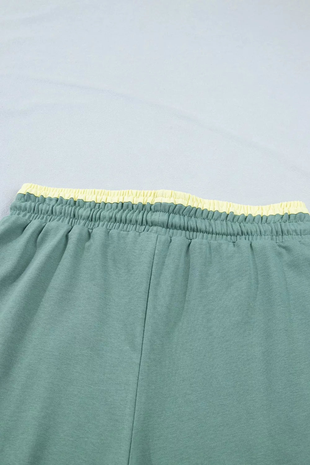 Green cotton sweatpants with yellow drawstring waist and wide legs.