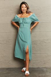 Teal dotted swiss off-shoulder midi dress with lace trim and a thigh slit.