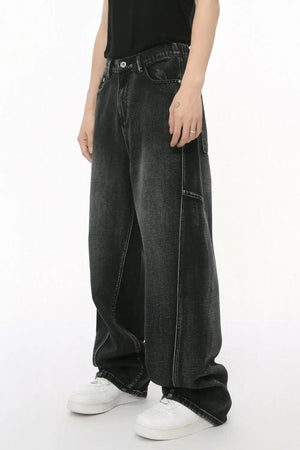 Dark wash denim trousers with exaggerated seam details and a relaxed fit.