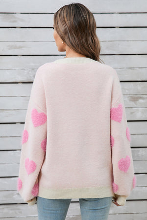 Blush pink knit sweater with fluffy pink heart appliques on the sleeves.