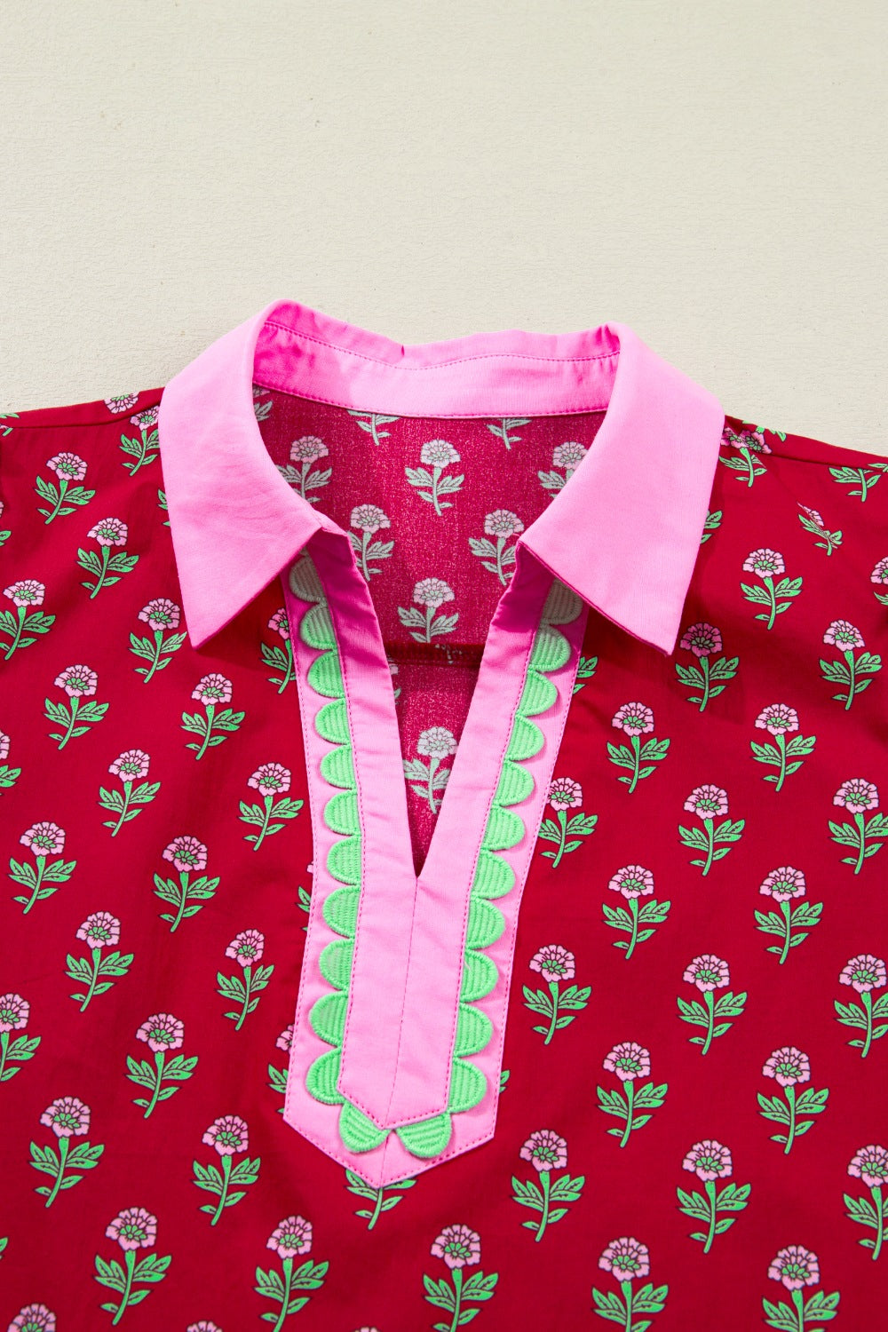 Red floral mini dress with pink collar, V-neck, and green scalloped trim